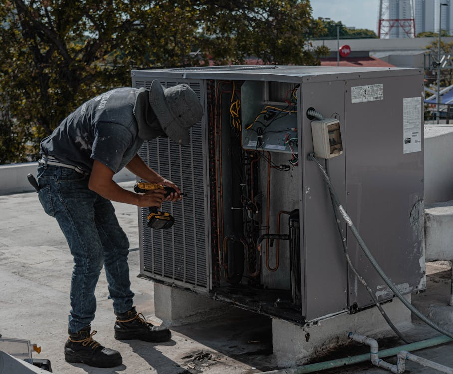A person repairing an outdoor HVAC unit